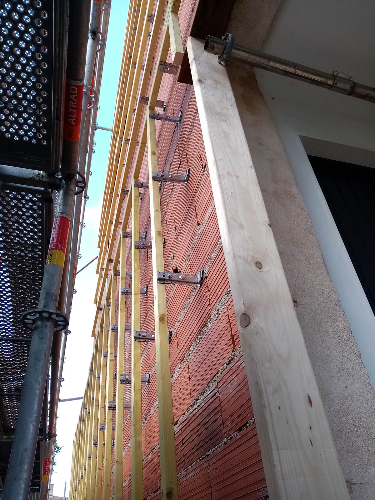 Ossature de fixation devant le mur en briques